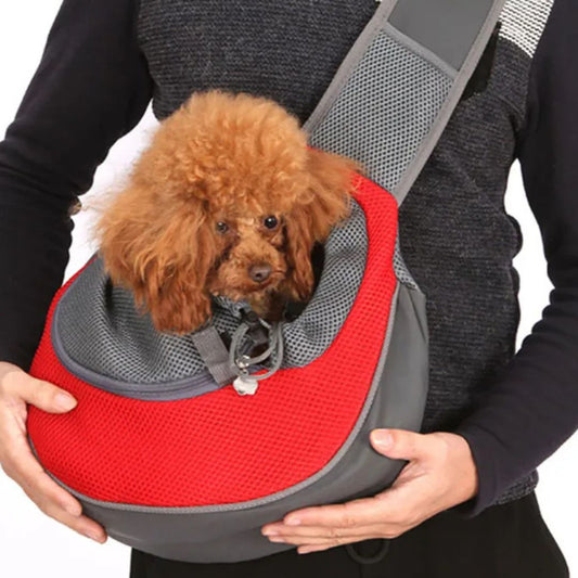 Person holding a small brown dog in a red and gray pet carrier.