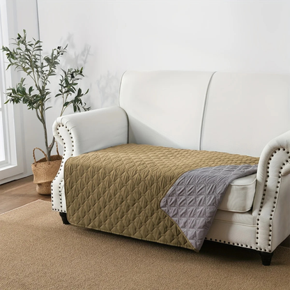 White sofa with beige quilted cover and gray blanket in a living room setting.