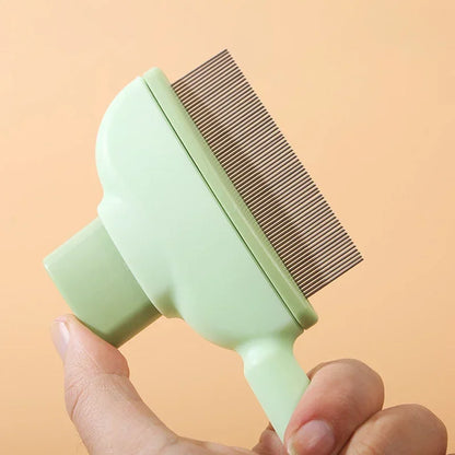 Green pet grooming brush held by a hand against a peach background